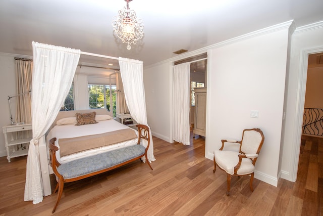 bedroom with an inviting chandelier, ornamental molding, and light wood-type flooring