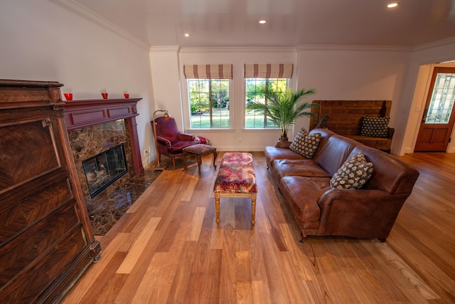 living room featuring crown molding, a high end fireplace, and light hardwood / wood-style floors