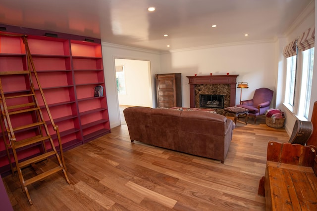 living room featuring a premium fireplace, ornamental molding, and light hardwood / wood-style floors