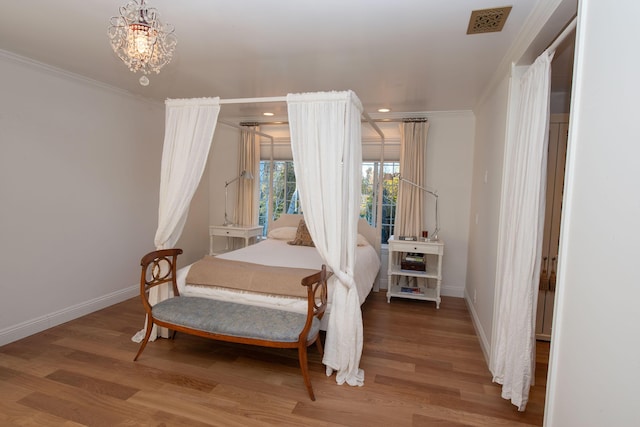 bedroom featuring a notable chandelier, crown molding, and wood-type flooring