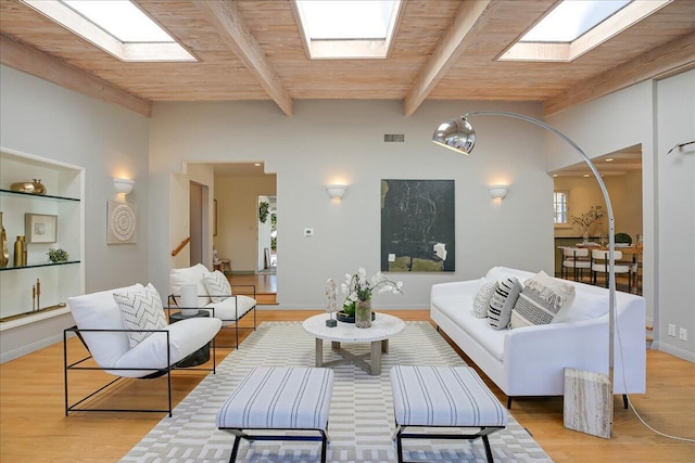 living room with a skylight, wood ceiling, light hardwood / wood-style flooring, and beamed ceiling