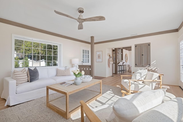 living room with ornamental molding, ceiling fan, and light hardwood / wood-style floors