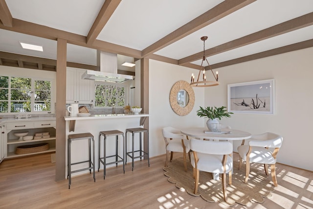 dining space featuring light wood-type flooring and beam ceiling