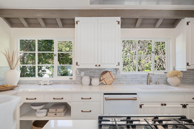 kitchen featuring beam ceiling, sink, white dishwasher, and backsplash