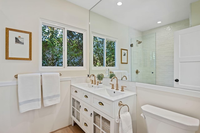 bathroom featuring toilet, tiled shower, and vanity