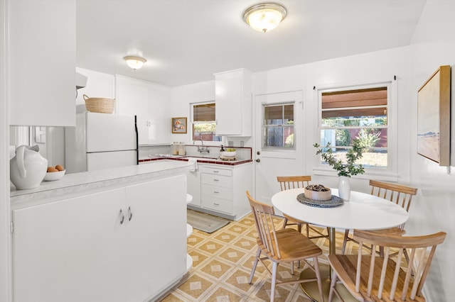 kitchen featuring white fridge, a healthy amount of sunlight, and white cabinets