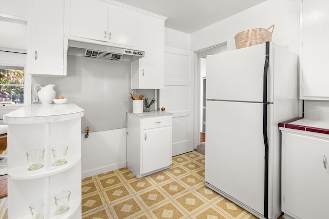 kitchen featuring white fridge, tile countertops, and white cabinets