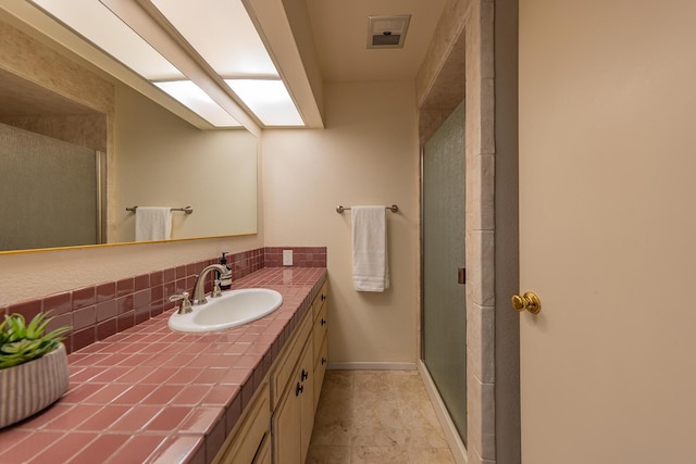 bathroom with tasteful backsplash, vanity, a shower with door, and a skylight