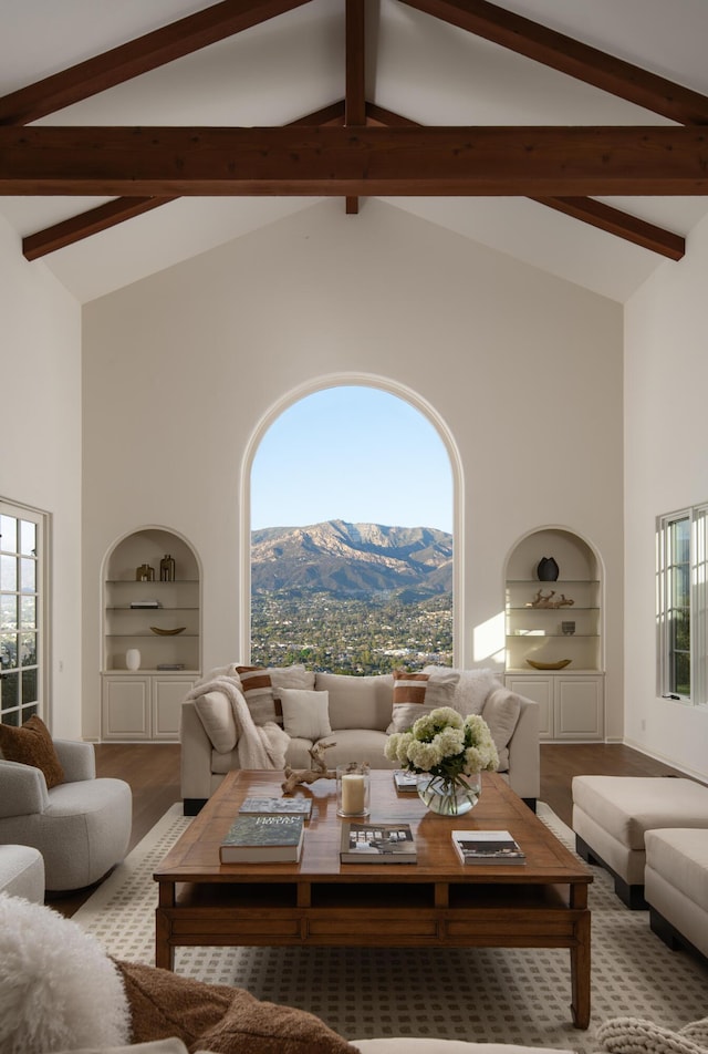 living room featuring beam ceiling, a mountain view, and built in shelves