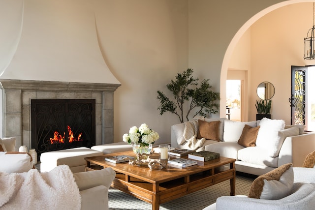 living room featuring a tiled fireplace and a towering ceiling