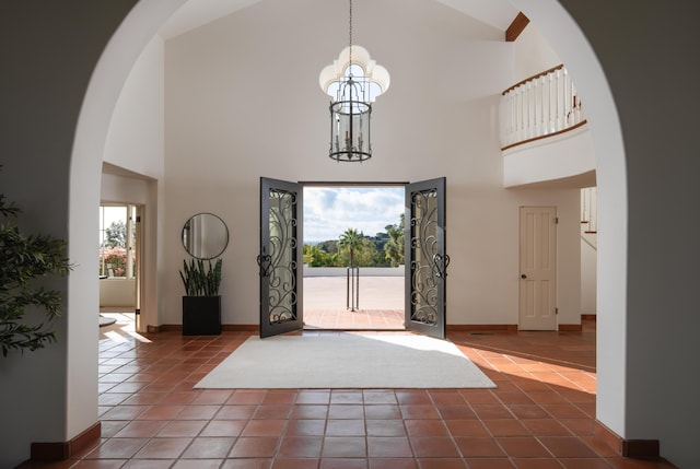 entrance foyer featuring a notable chandelier, a towering ceiling, and dark tile patterned floors