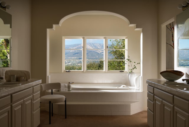 bathroom with tiled tub, vanity, and a mountain view