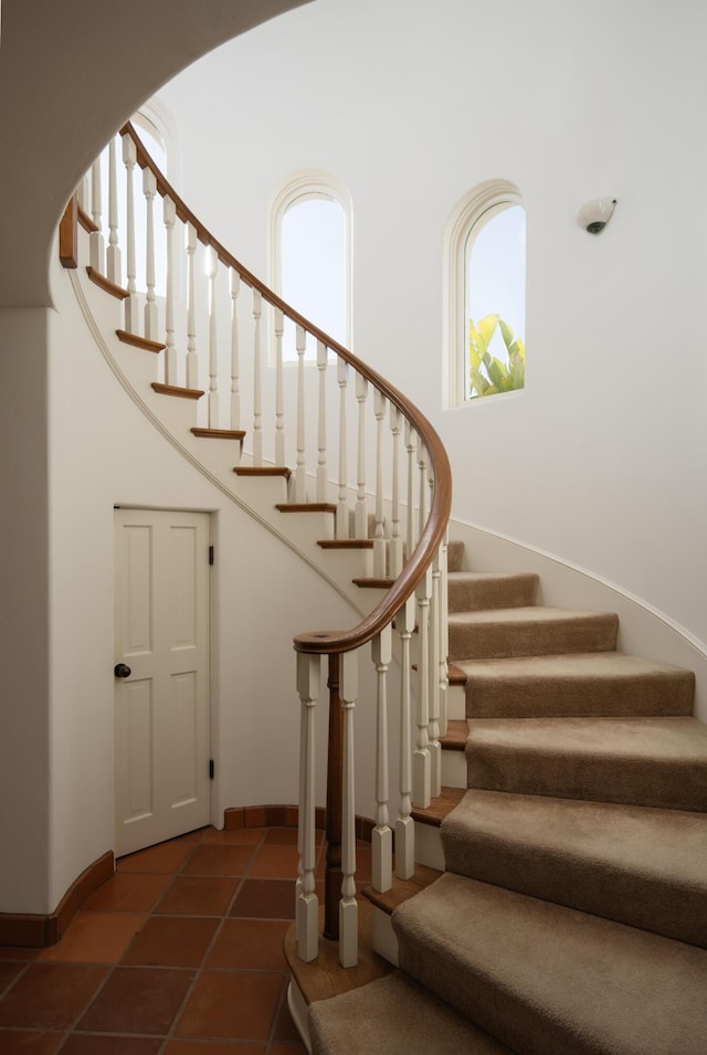 staircase with tile patterned flooring and a high ceiling