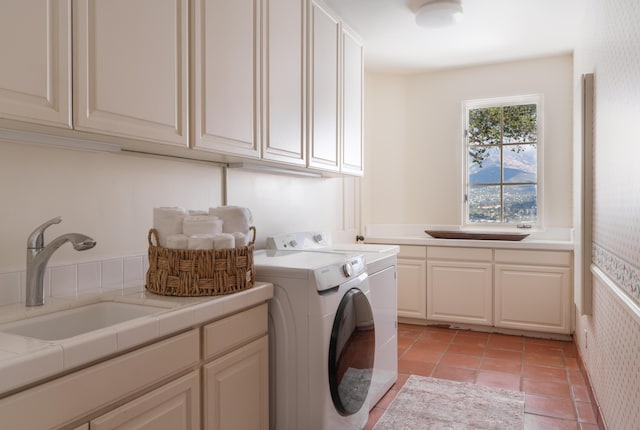 laundry area with cabinets, washer and clothes dryer, sink, and light tile patterned floors