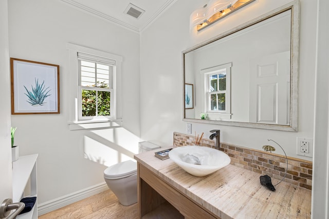 bathroom with toilet, ornamental molding, vanity, hardwood / wood-style flooring, and decorative backsplash