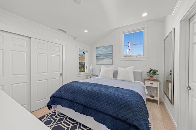 bedroom featuring multiple windows, light hardwood / wood-style floors, a closet, and lofted ceiling