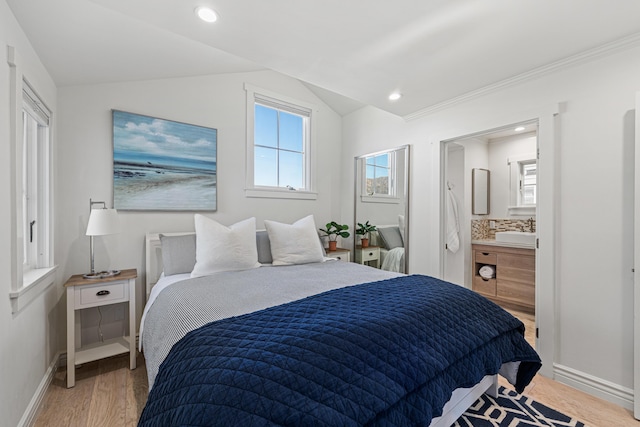 bedroom with vaulted ceiling, wood-type flooring, sink, and ensuite bath