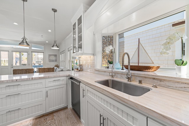 kitchen with sink, dishwasher, hanging light fixtures, and white cabinets