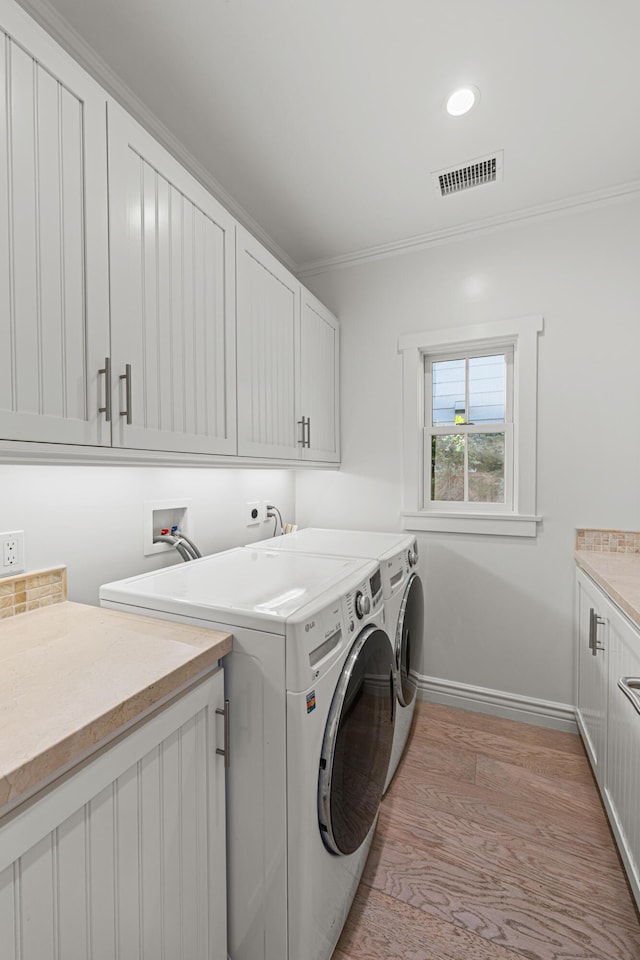 washroom featuring independent washer and dryer, cabinets, ornamental molding, and light hardwood / wood-style floors