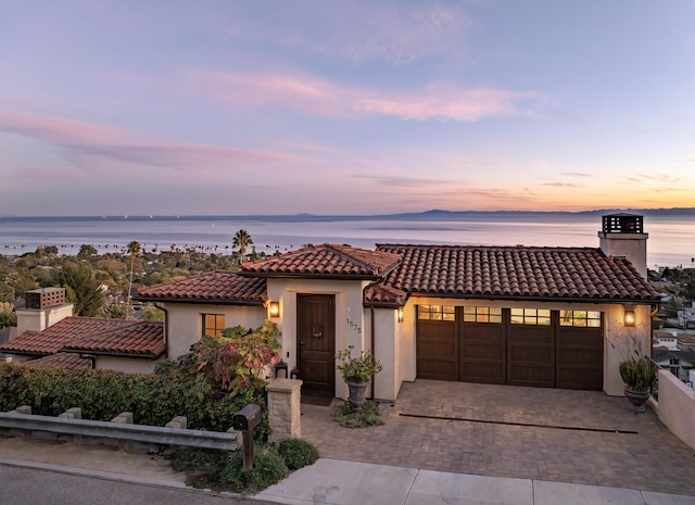 mediterranean / spanish-style home with a garage and a water view