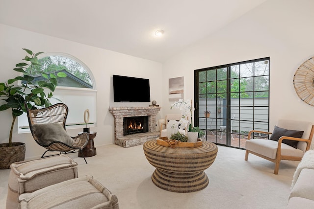 carpeted living room featuring a stone fireplace and vaulted ceiling