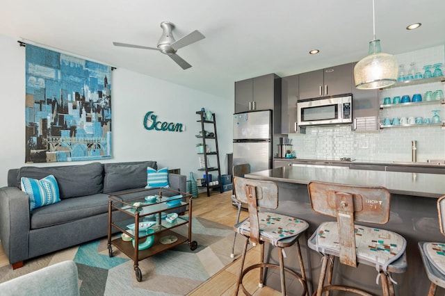 living room featuring sink, light hardwood / wood-style floors, and ceiling fan