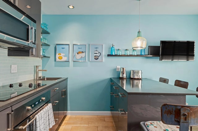 kitchen with a breakfast bar, sink, hanging light fixtures, stainless steel appliances, and backsplash