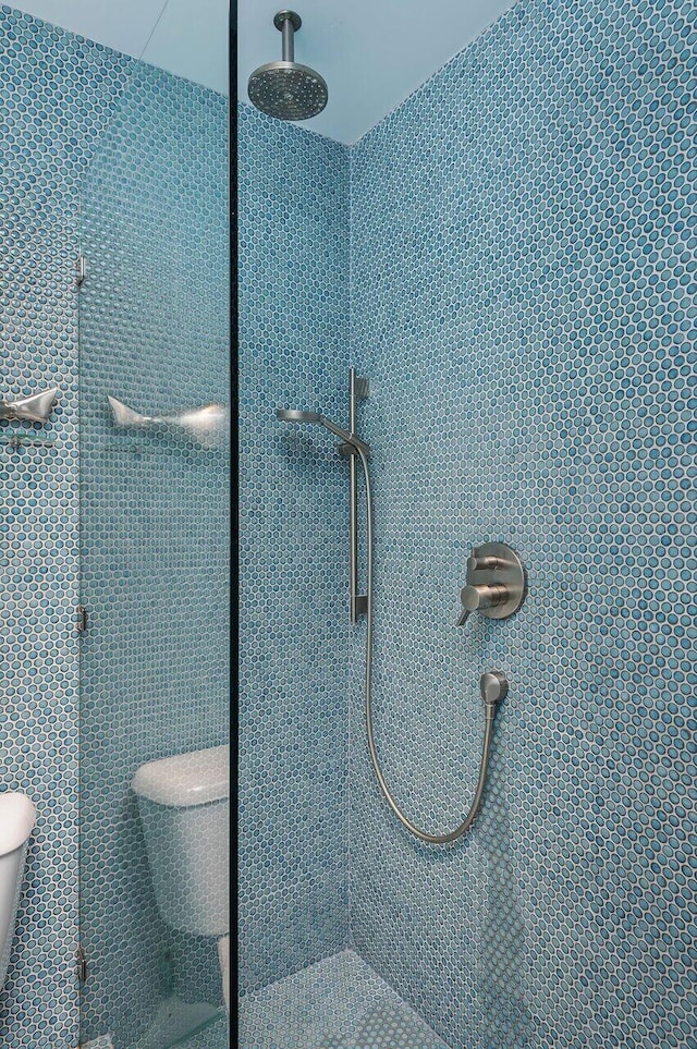 interior details with a tile shower and toilet