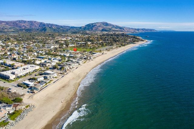 drone / aerial view featuring a water and mountain view and a beach view