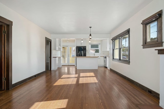 kitchen with french doors, black refrigerator, white cabinets, pendant lighting, and stove