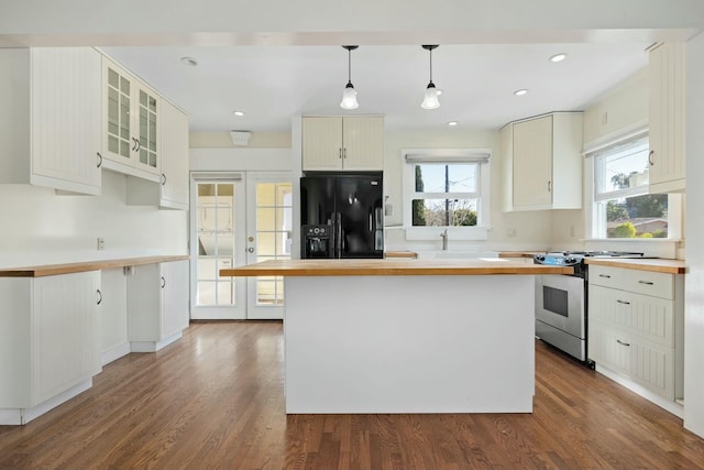 kitchen with black fridge, pendant lighting, a kitchen island, and stainless steel gas stove