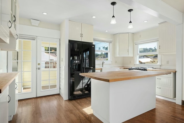 kitchen featuring pendant lighting, butcher block countertops, a kitchen island, black fridge with ice dispenser, and french doors