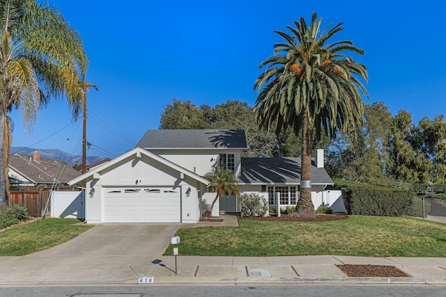 view of front facade featuring driveway, a gate, fence, a front yard, and an attached garage