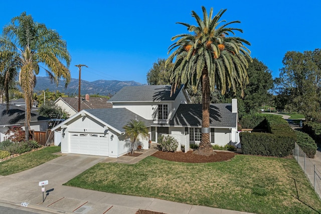 view of front facade with a front yard, fence, an attached garage, a shingled roof, and concrete driveway