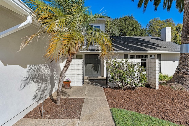 doorway to property featuring roof with shingles