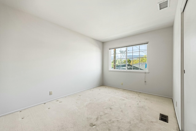 empty room featuring carpet, visible vents, and baseboards