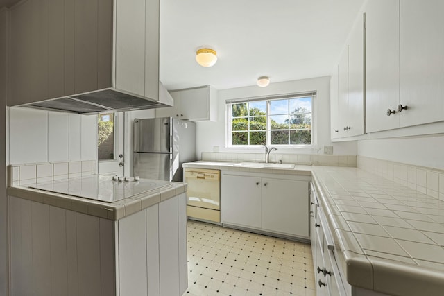 kitchen with tile countertops, extractor fan, freestanding refrigerator, dishwasher, and light floors