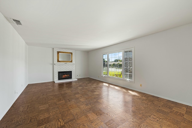 unfurnished living room featuring a brick fireplace, baseboards, and visible vents