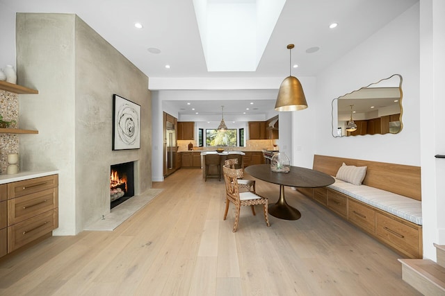 dining space featuring a premium fireplace, light hardwood / wood-style floors, and a skylight