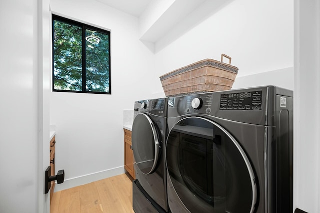 laundry area with cabinets, washer and dryer, and light hardwood / wood-style flooring