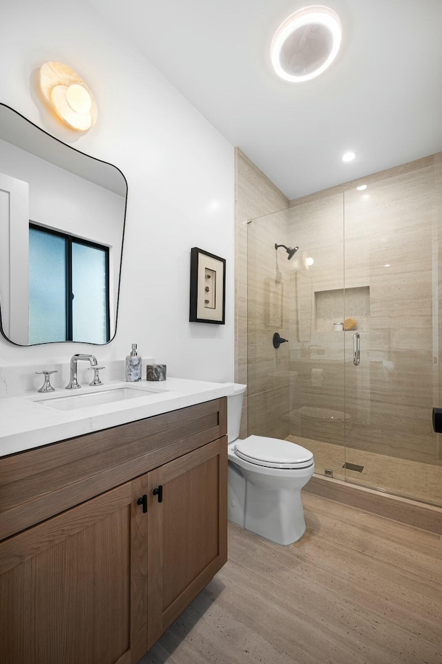 bathroom featuring hardwood / wood-style flooring, vanity, toilet, and a shower with shower door