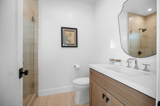 bathroom with hardwood / wood-style flooring, vanity, toilet, and a shower with shower door