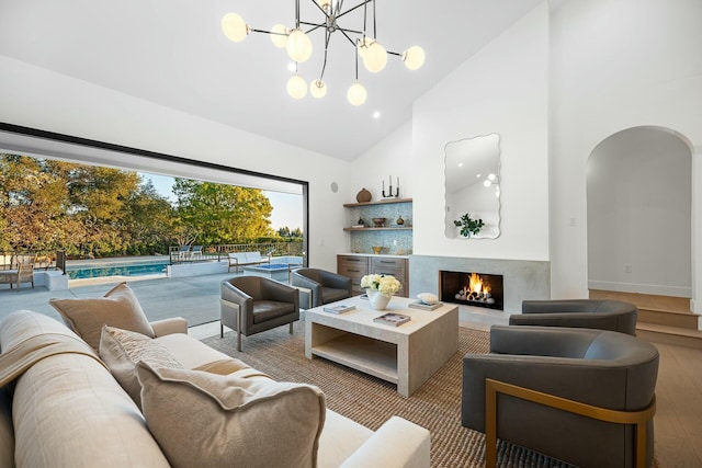 living room featuring an inviting chandelier, light hardwood / wood-style floors, high vaulted ceiling, and a premium fireplace