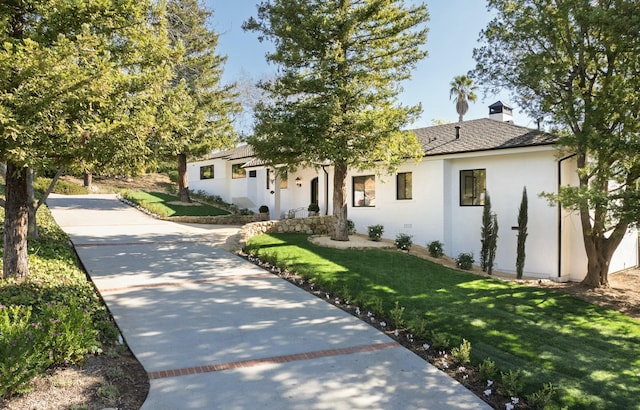 ranch-style house with a front yard, concrete driveway, and a chimney