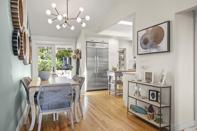 dining area with french doors, lofted ceiling, light hardwood / wood-style floors, and a notable chandelier