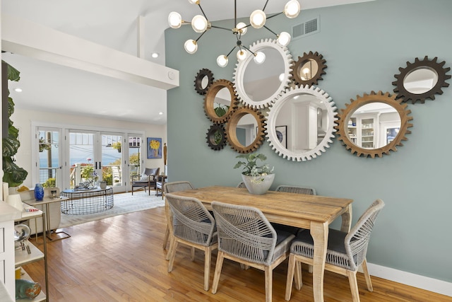 dining area featuring a notable chandelier, hardwood / wood-style flooring, and french doors