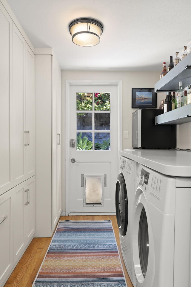 washroom with light hardwood / wood-style floors and washer and dryer