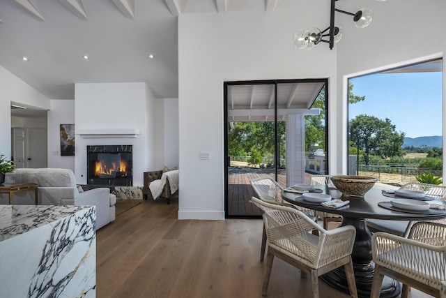 dining space with beam ceiling, hardwood / wood-style floors, and a chandelier