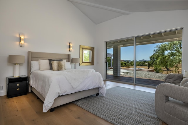 bedroom featuring lofted ceiling with beams, access to exterior, and light hardwood / wood-style flooring