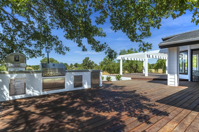 wooden terrace featuring area for grilling, a pergola, and an outdoor kitchen